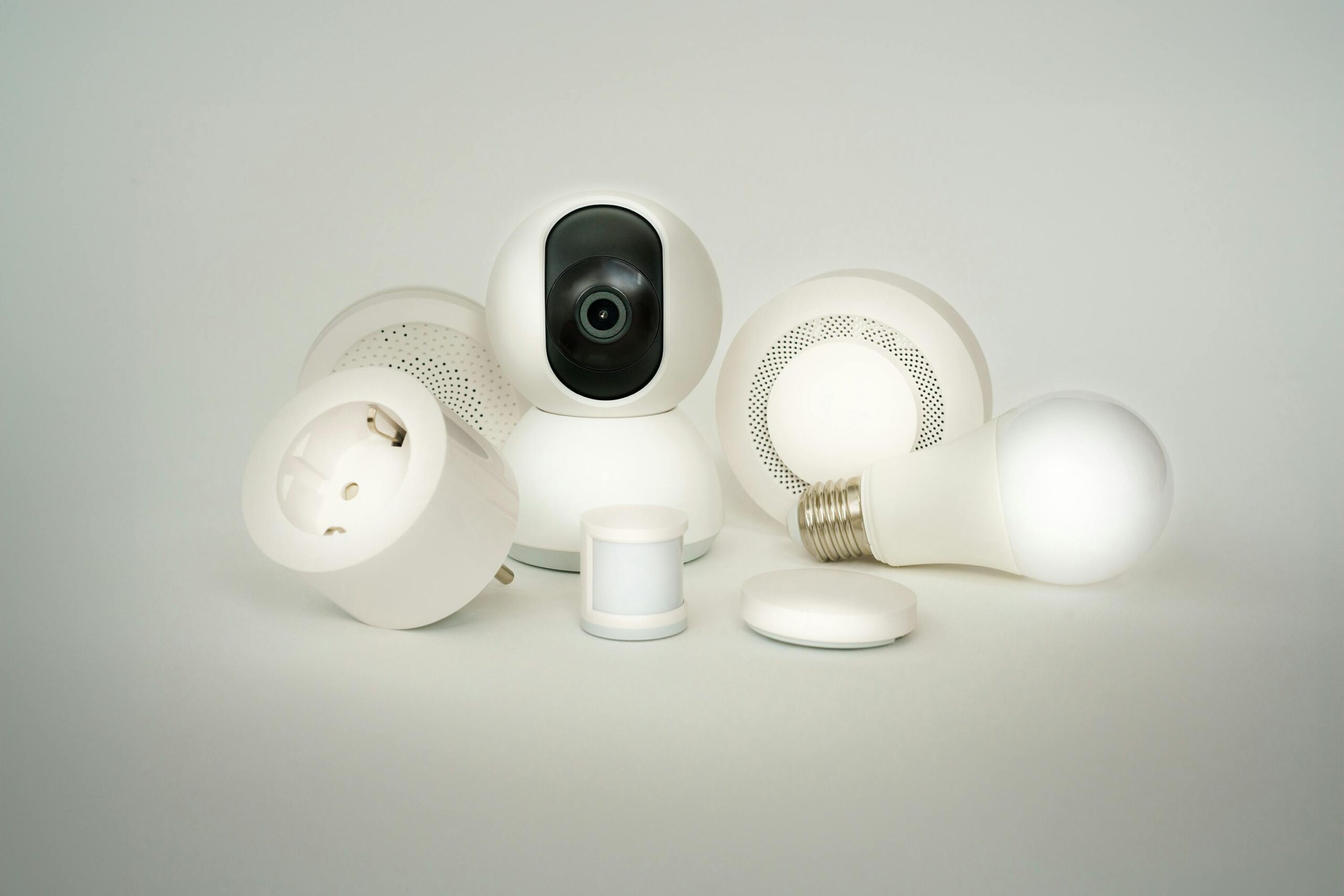 A collection of smart home devices including bulbs, sockets, and cameras on a white backdrop.